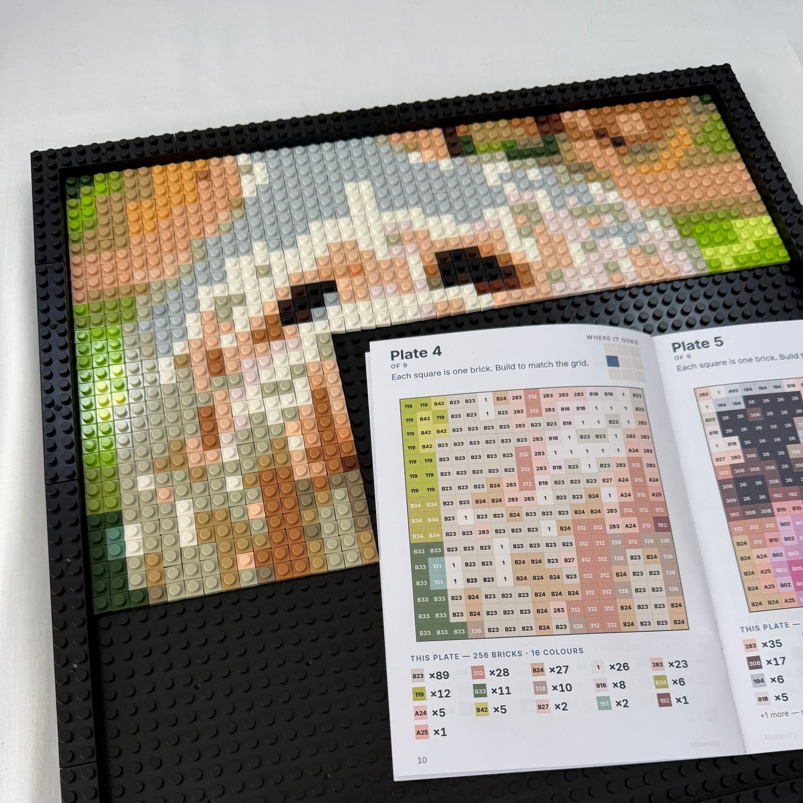 The dog's face half-built in bricks with the build booklet on the board