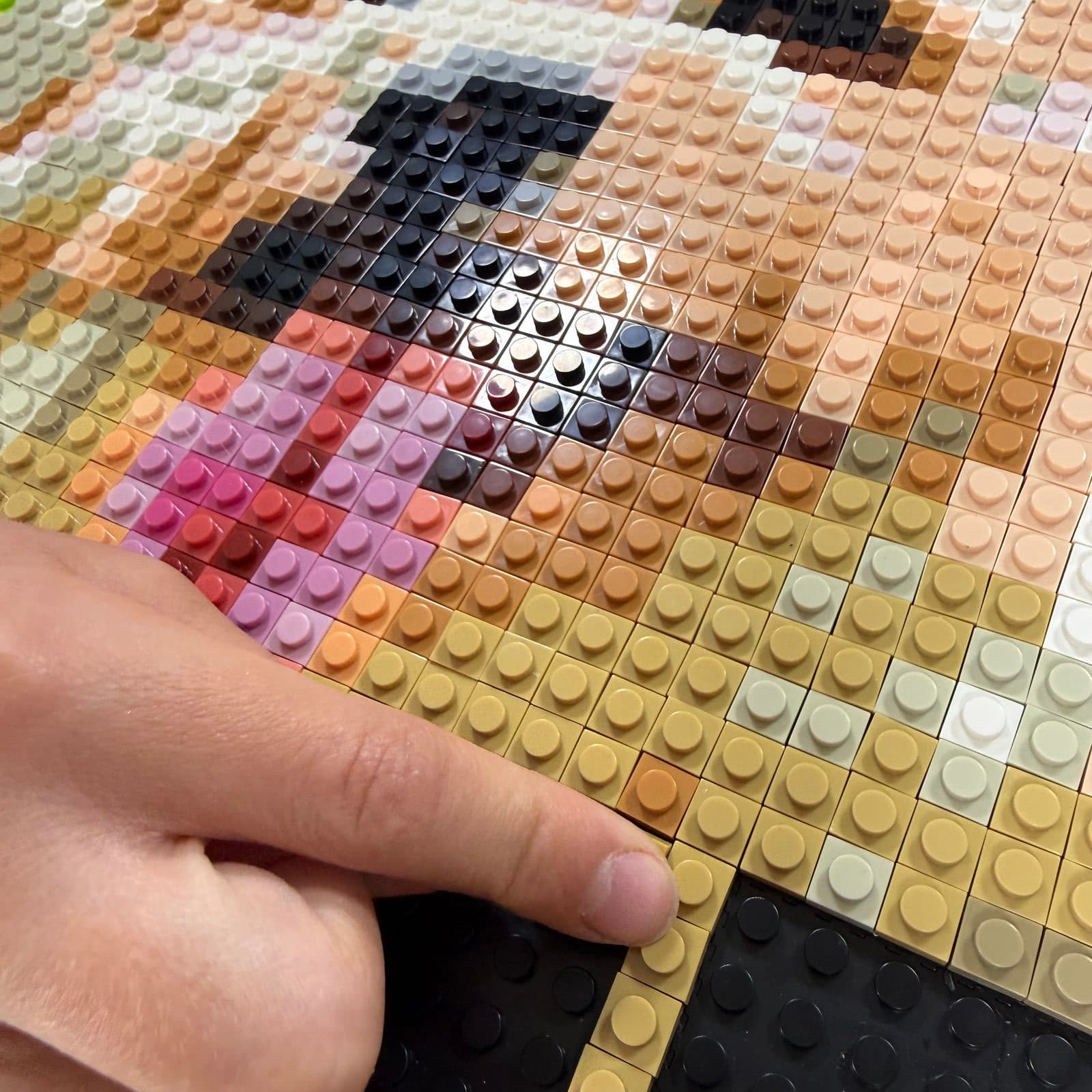 A thumb pressing one of the final bricks into the mosaic